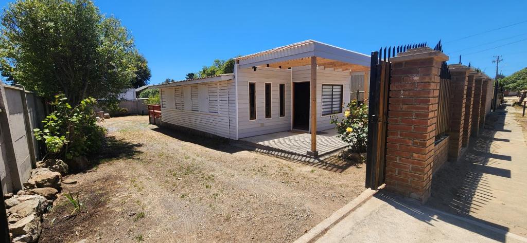 a small white house with a fence around it at Cabaña Familiar 3 dormitorios 1 baño gran espacio para compartir in El Quisco