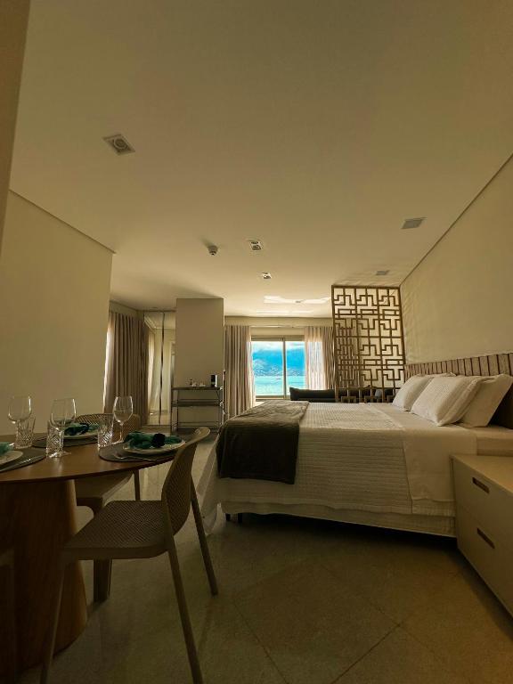 a bedroom with a large bed and a table and a desk at Ágape Suítes & Apartamentos in São Sebastião