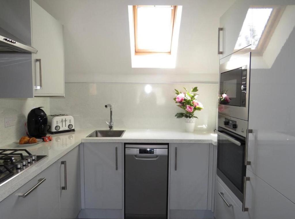 uma cozinha com armários brancos, um lavatório e uma janela em Bradford Drive em Mile End