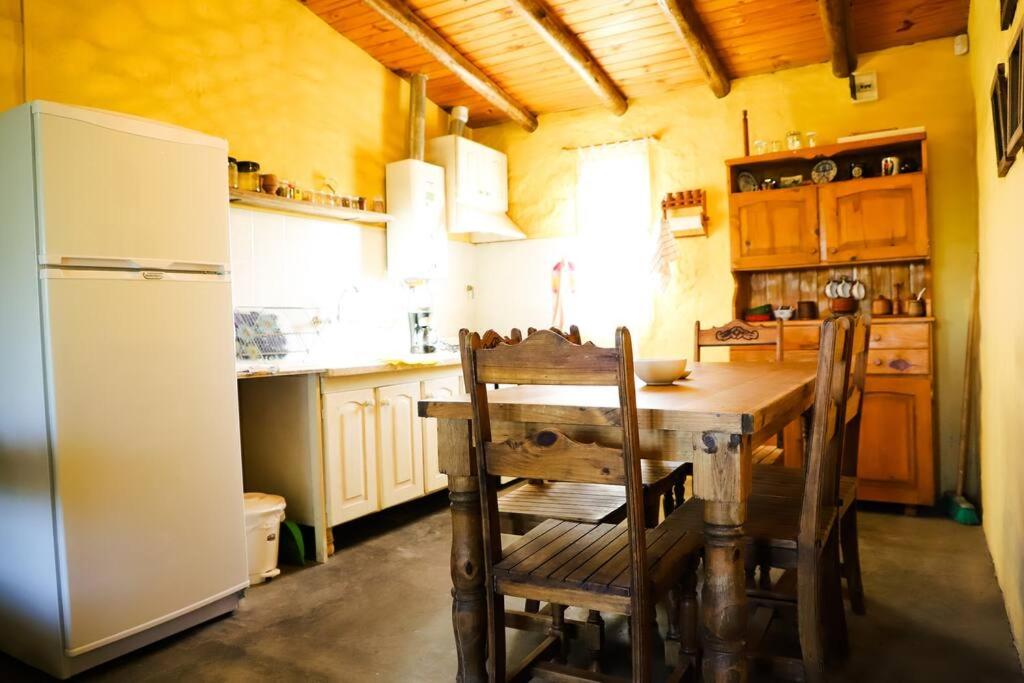 eine Küche mit Holztisch und Kühlschrank in der Unterkunft Colonia Indalo casa de campo in San Carlos