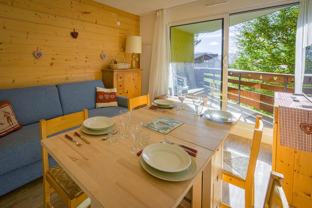 une salle à manger avec une table en bois, des assiettes et des verres dans l'établissement Studio Pastilla - Welkeys, à Huez