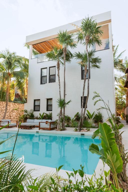 a villa with a swimming pool and palm trees at Elements Rituals Beachfront Bahia Soliman Tulum in Tulum