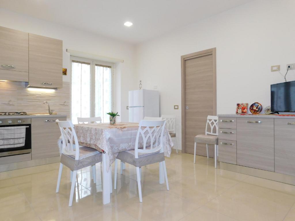 uma cozinha com uma mesa com cadeiras e um frigorífico em Cariteo Home em Nápoles