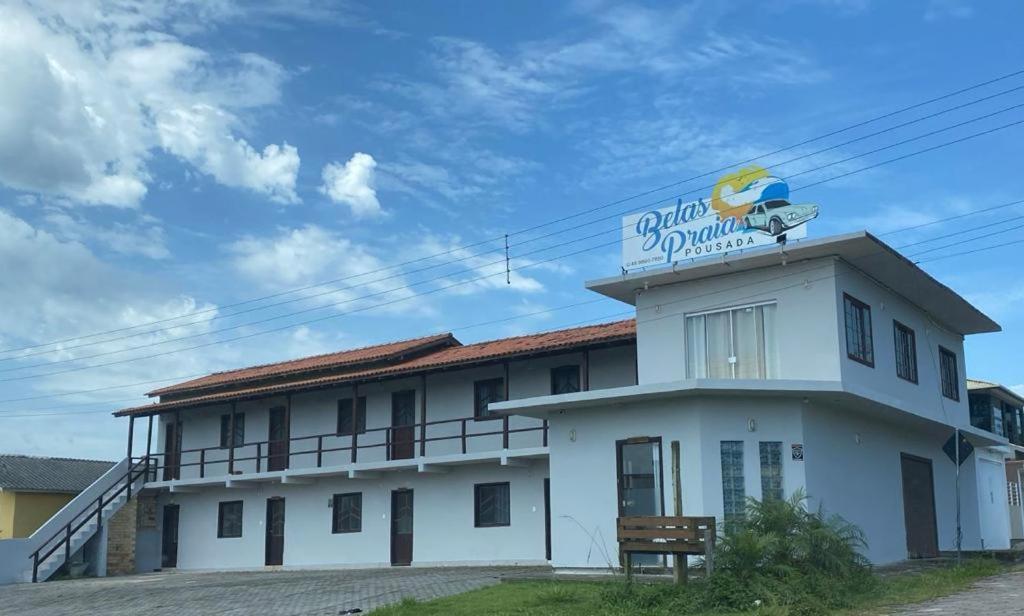 a white building with a sign on top of it at Pousada Belas Praia - Ribanceira in Imbituba
