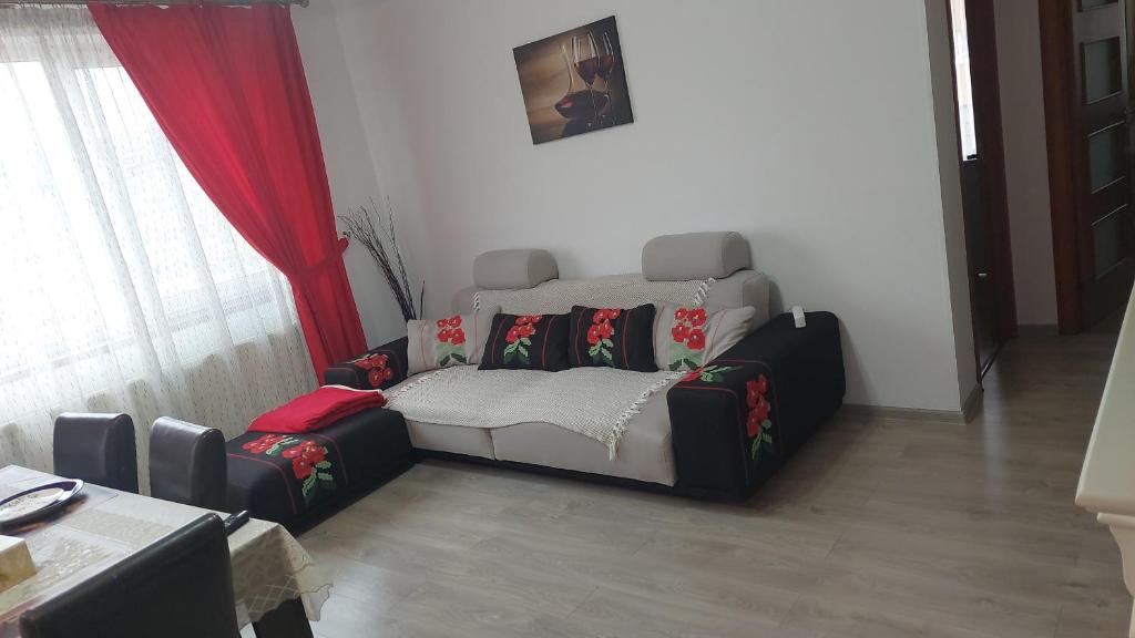 sala de estar con sofá y cortinas rojas en RentForComfort Charming Flat in Bistrita, en Bistriţa