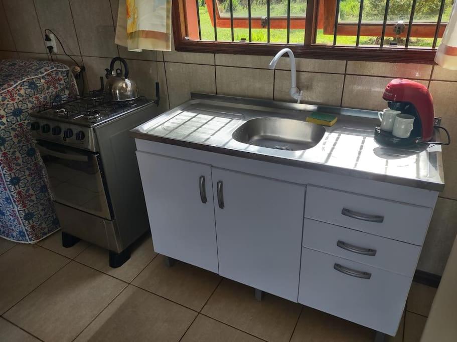 a small kitchen with a sink and a stove at Pousada da Lua in Rolante