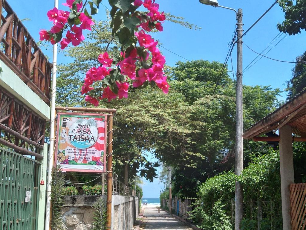 a street with a sign and pink flowers at Hostal Casa Taisha in Montañita