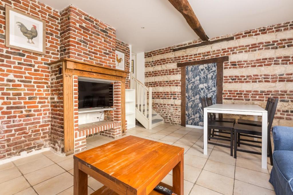 salon ze ścianą z cegły i stołem w obiekcie Maison Juliette, maison à la campagne w mieście Comines