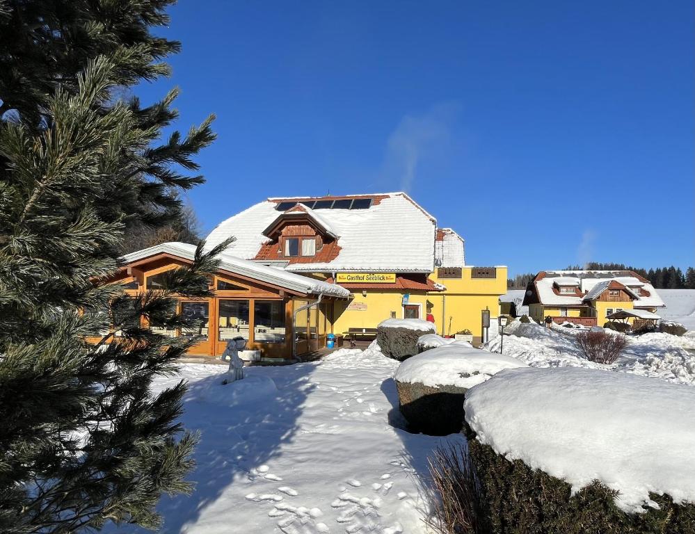 una casa cubierta de nieve delante en Hotel Gasthof Seeblick, en Zeutschach