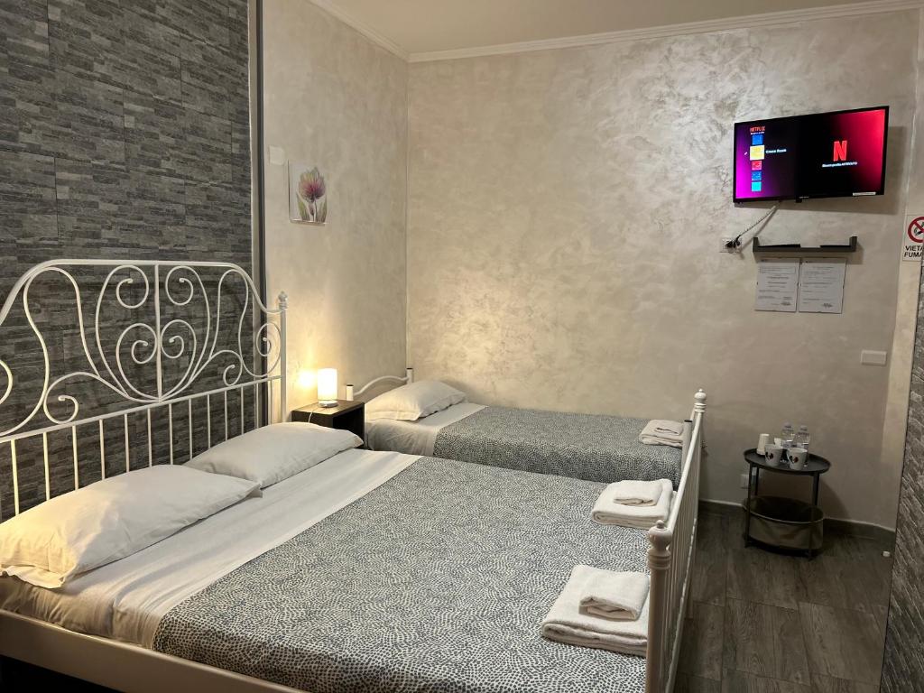 a bedroom with two beds and a tv on the wall at RooMYitalia - Guest House Il Faraone in Fiumicino