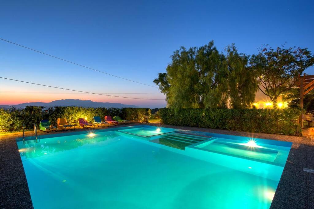una gran piscina con luces en el patio trasero por la noche en Villa Kapodistria, en Moúlete