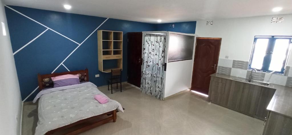 1 dormitorio con cama y pared azul en JC ITEN Guest House en Iten