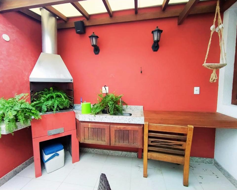 an outdoor kitchen with a red wall at Casa da alegria 4 quartos centro histórico in Itaparica