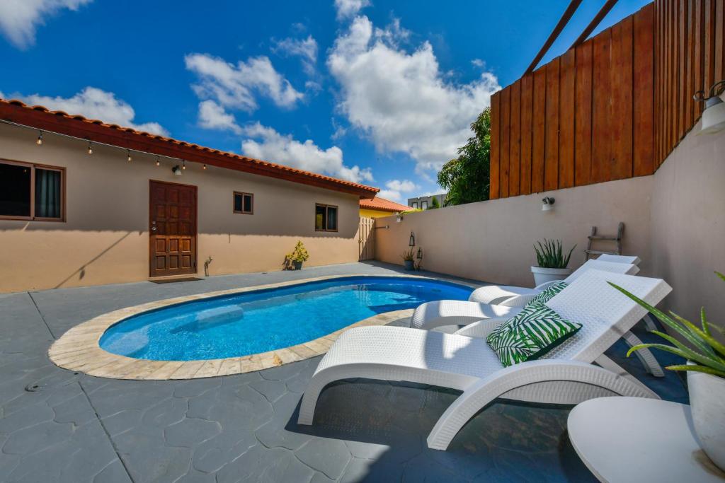 a swimming pool with chairs and a house at Felicidad 30 in Oranjestad