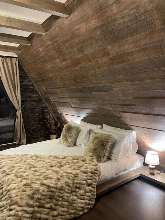 a bedroom with a large bed with a wooden wall at Valea Mosului - Chic A Frame in Petroşani