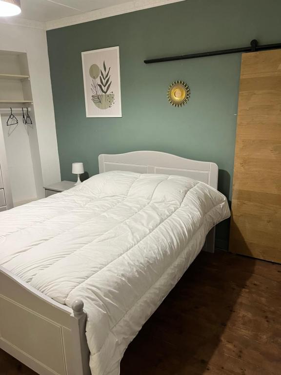 a white bed in a bedroom with a blue wall at Petite maison sympa in Saint-Jean-sur-Mayenne