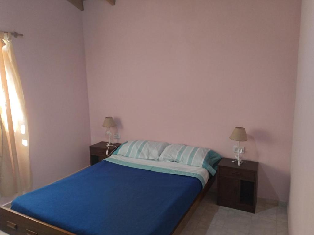 1 dormitorio con 1 cama con sábanas azules y 2 mesas en Km 9 en Viedma