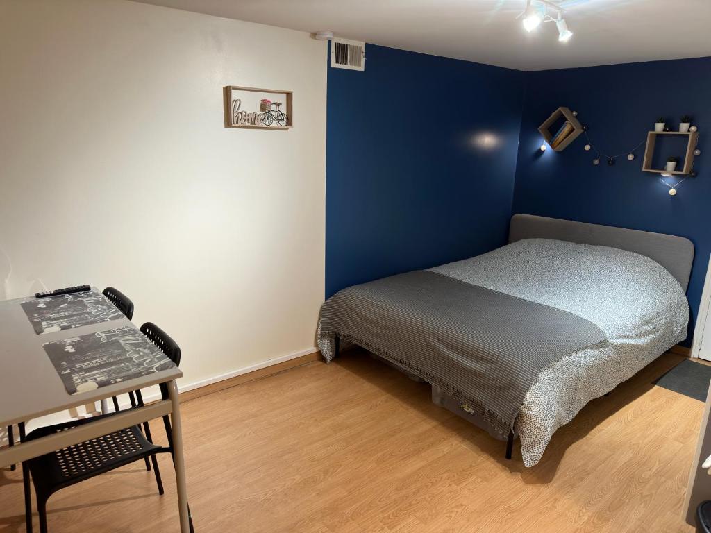 ein blaues Schlafzimmer mit einem Bett und einem Tisch in der Unterkunft Studio proche forêt in Montmorency