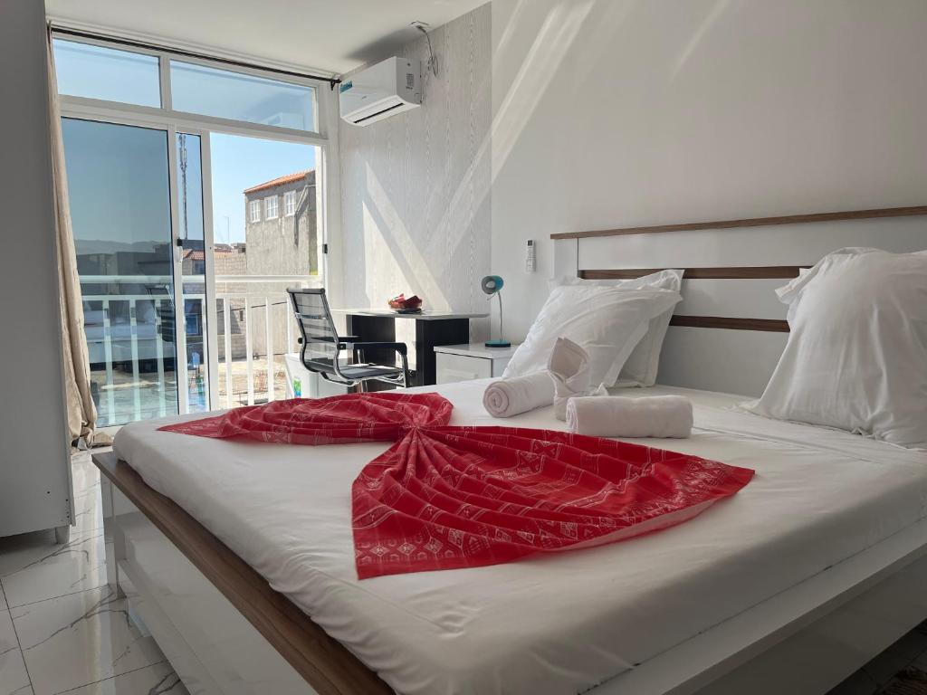 a bedroom with a bed with a red blanket on it at Hotel Principal in Tarrafal