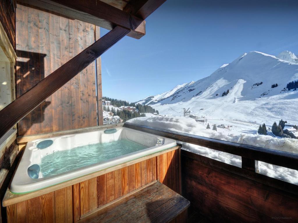 a hot tub on the side of a building with a snow covered mountain at Chalet Capieu - Le Barn - OVO Network in Manigod