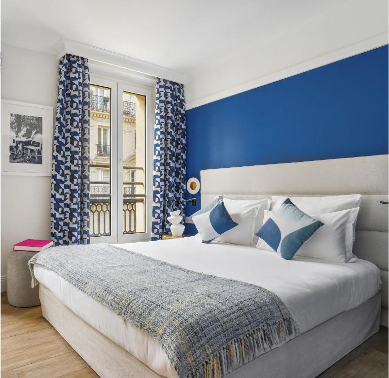 - une chambre avec un grand lit et un mur bleu dans l'établissement Hotel Elysees Opera, à Paris