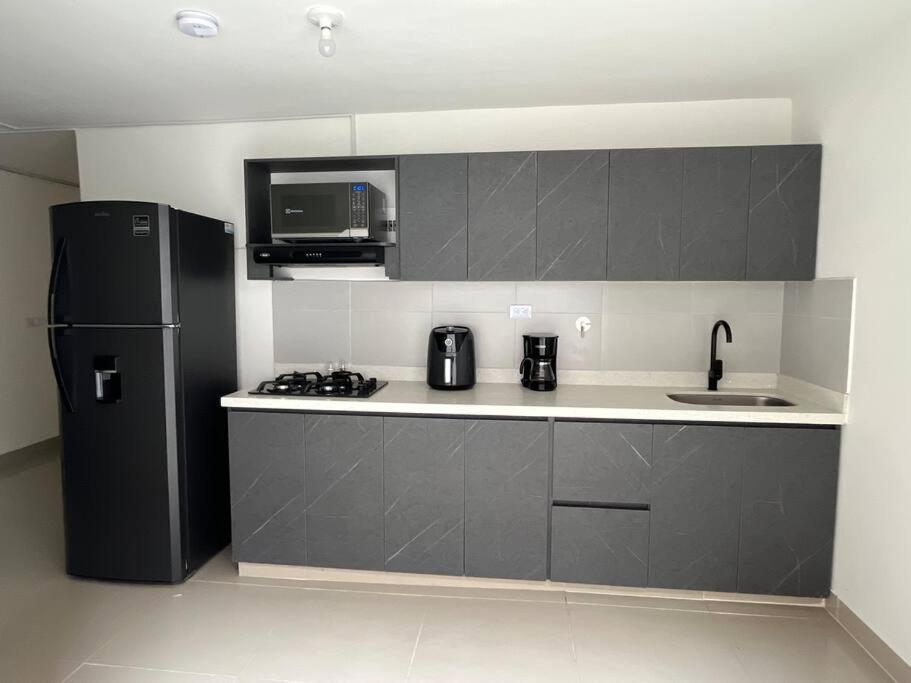 a kitchen with a black refrigerator and a sink at Traditional Roomy House in Medellín