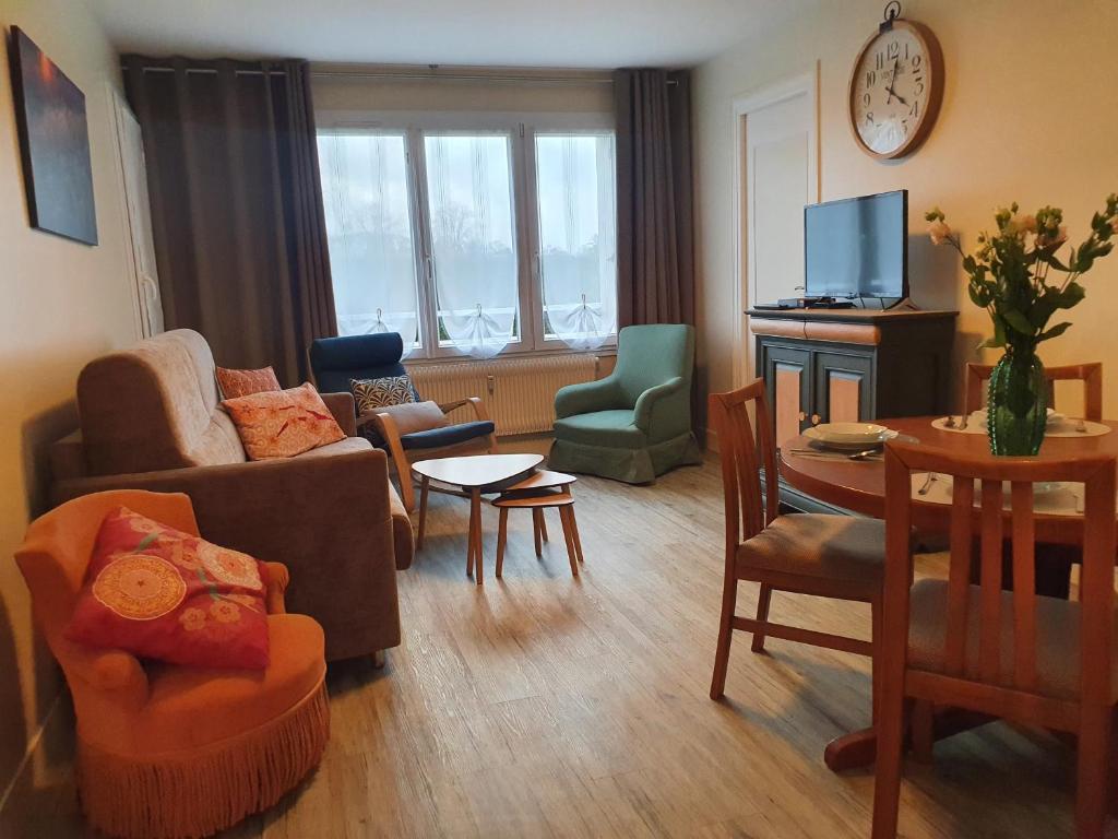 ein Wohnzimmer mit Möbeln und einem Tisch in der Unterkunft Chemin vert in Bayeux