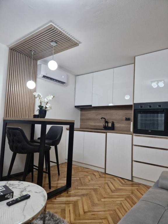 a kitchen with white cabinets and a table at Stan na dan Jelica Stanivuković in Šid