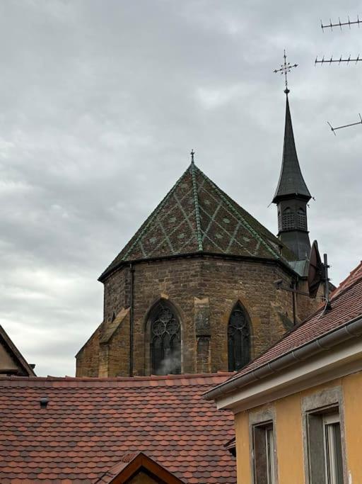 une ancienne église avec une cloche au-dessus d'un toit dans l'établissement Suites du trèfle, à Colmar