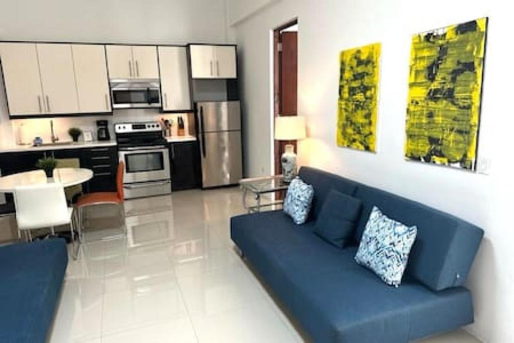 KASA The Lofts 304 في سان خوان: غرفة معيشة مع أريكة زرقاء ومطبخ