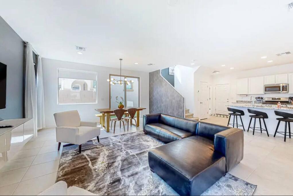 a living room with a leather couch and a kitchen at The Spotless 2 Story in Phoenix