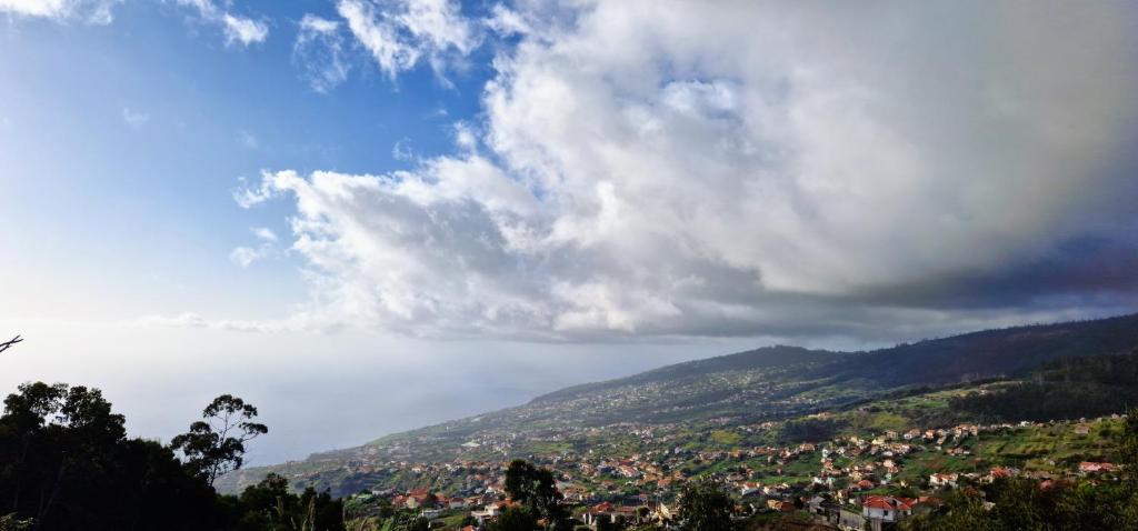 a view of a town on a hill with clouds at Madeira Mountain Paradise - Casa da Levada do Arco in Arco da Calheta