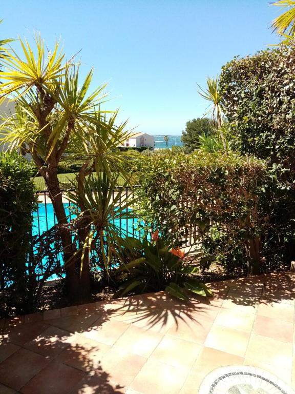 une piscine avec des palmiers et une clôture dans l'établissement T2 DANS DOMAINE PRIVE PISCINE TENNIS PARC PARC AQUATIQUE VUE MER ET PLAGE, à Six-Fours-les-Plages