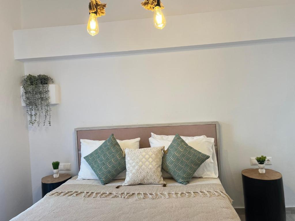 a bedroom with a bed with pillows and lights at Aleria Central Apartment 2 in Naxos Chora