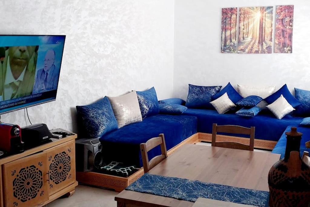 un soggiorno con un divano blu e una TV di Bel appartement calme est bien équipé a Meknès