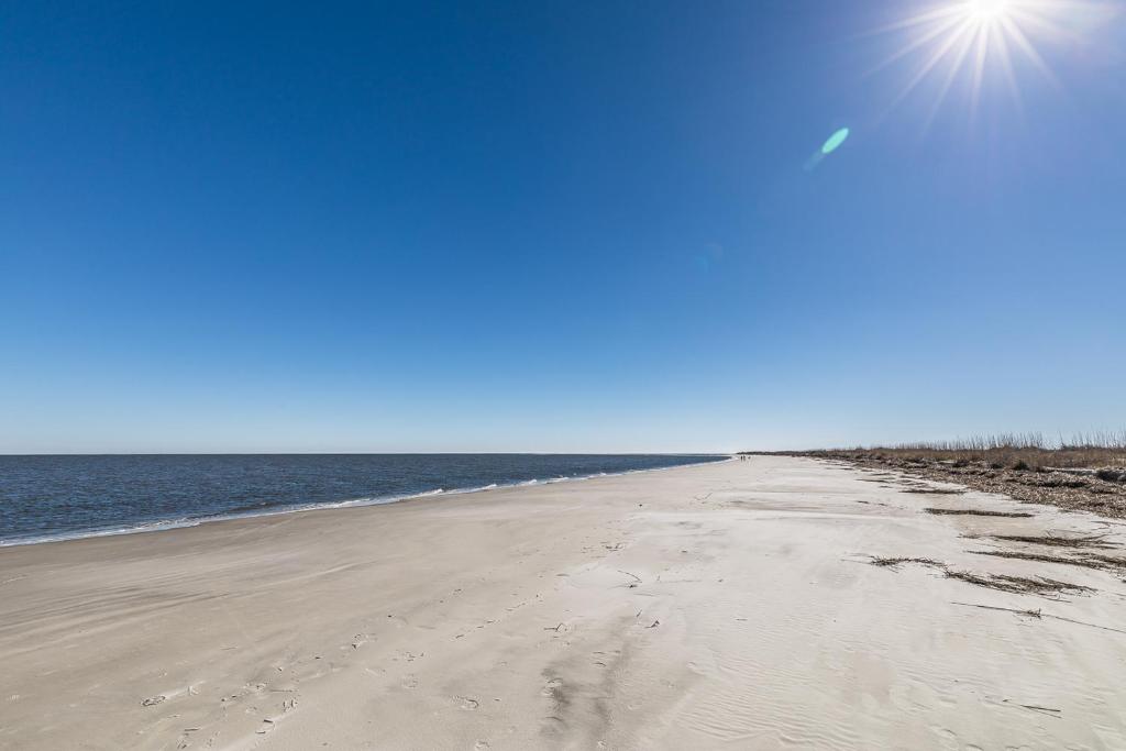 an empty beach with the sun in the sky at Direct Ocean View! M Building Pool and Ocean Views in Harbor Island