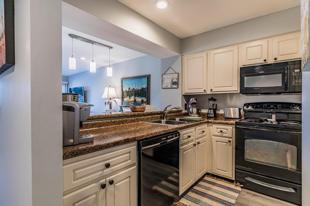 a kitchen with white cabinets and black appliances at Direct Ocean View! M Building Pool and Ocean Views in Harbor Island