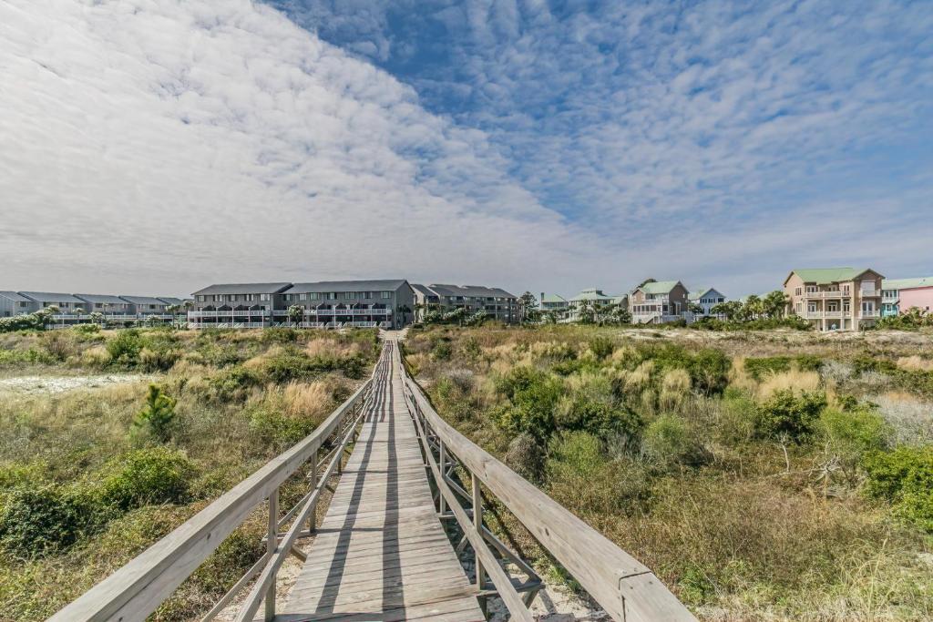 a wooden bridge over a beach with houses in the background at Direct Ocean View! M Building Pool and Ocean Views in Harbor Island