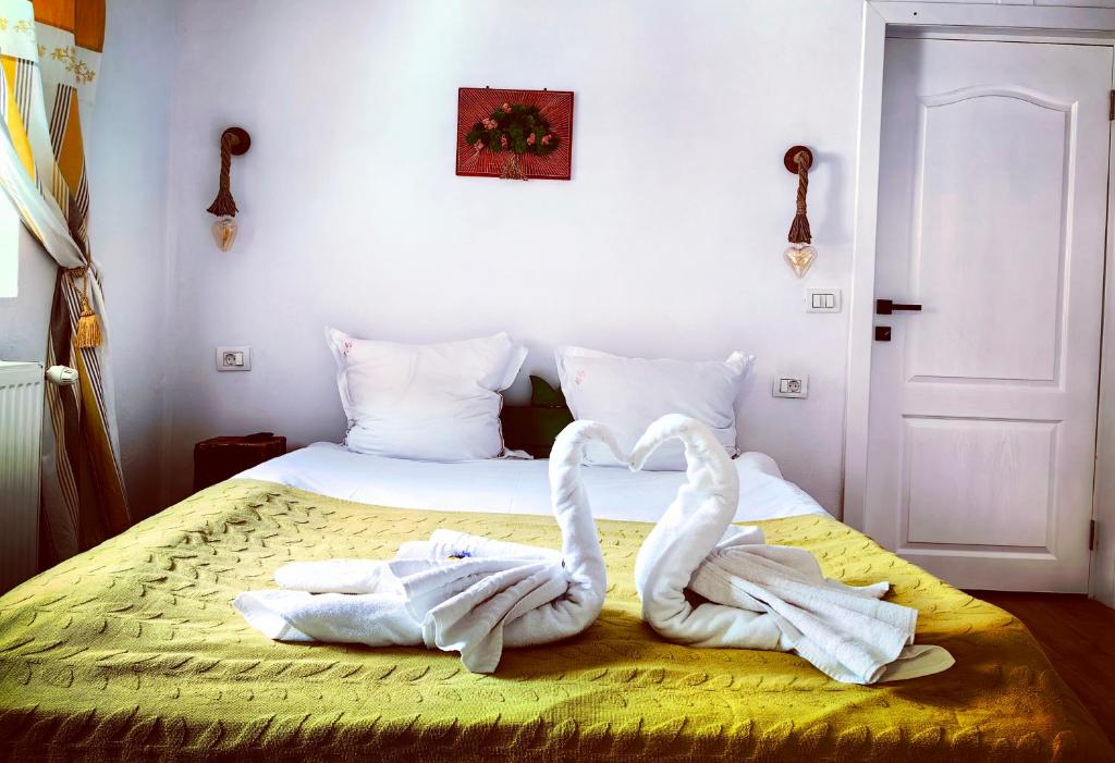 two towel swans making a heart on a bed at Voinescu House - Natural Living & Eating in Şimon
