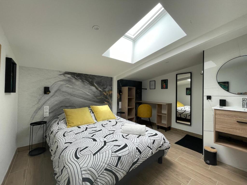 um quarto com uma cama com almofadas amarelas e uma clarabóia em Résidence Tamaris Loft House em La Mézière
