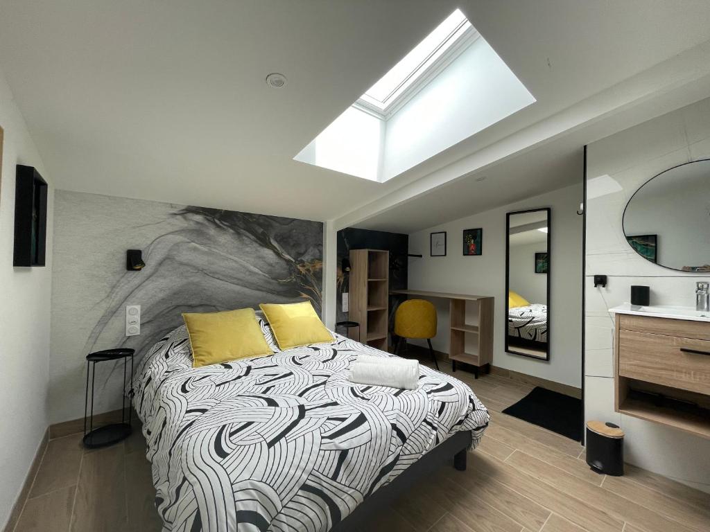 a bedroom with a bed with yellow pillows and a skylight at Résidence Tamaris Loft House in La Mézière