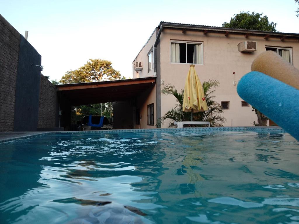 una piscina frente a una casa con sombrilla en CardónApart en Puerto Iguazú