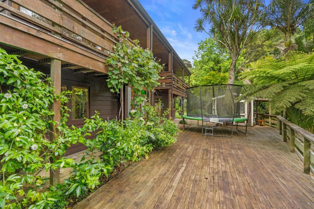 an outdoor deck of a house with plants and a table at Treetop Sanctuary - Titirangi Holiday Home in Auckland