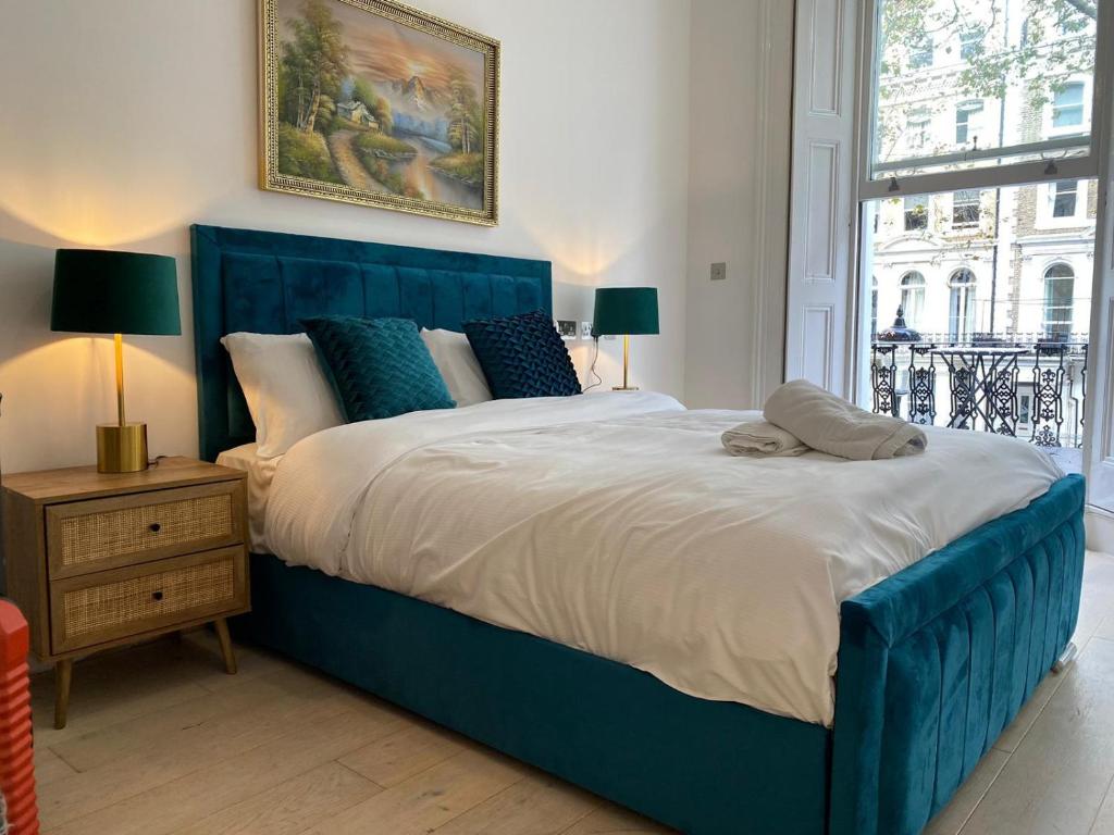 a large blue bed in a room with a window at The Chapter- Knightsbridge Suites in London