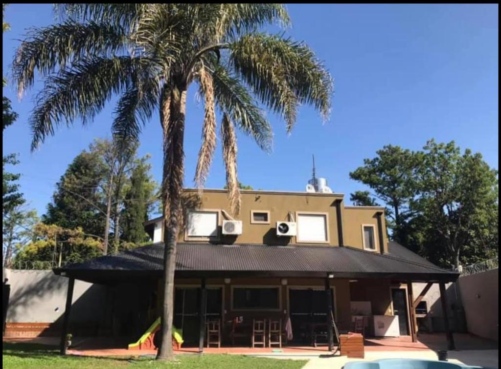 uma casa com duas palmeiras em frente em Casa quinta tortugas golf em Manuel Alberti