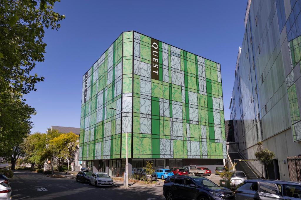a green glass building with cars parked in front of it at Quest on Cambridge in Christchurch