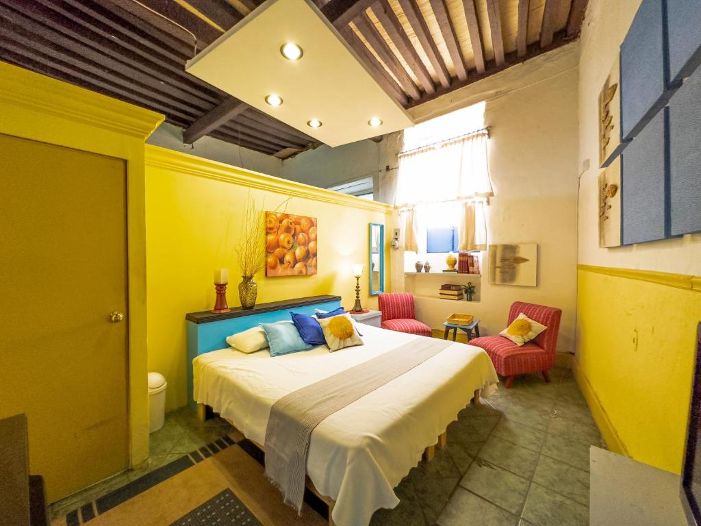 1 dormitorio con 1 cama grande y 2 sillas en La Casa Azul, en Morelia