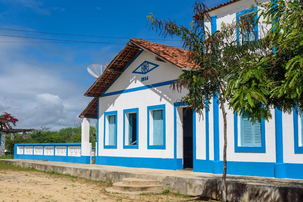 niebiesko-biały budynek z drzewem z przodu w obiekcie Fazenda Poço das Pedras w mieście São João do Cariri