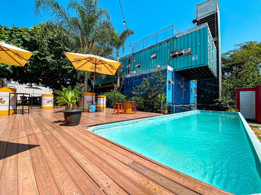 einen Pool auf einer Holzterrasse mit einem Sonnenschirm in der Unterkunft Tetris Container Hostel in Foz do Iguaçu
