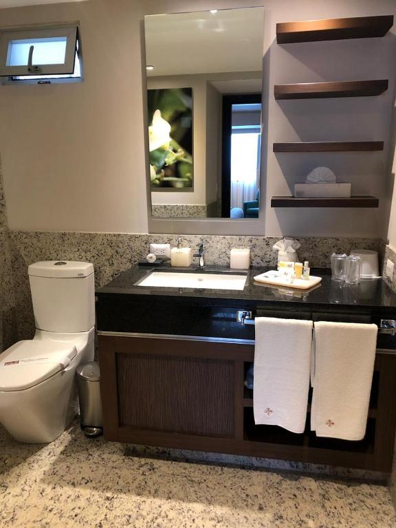 A compact bathroom with a granite vanity, toilet and wall-mounted television.